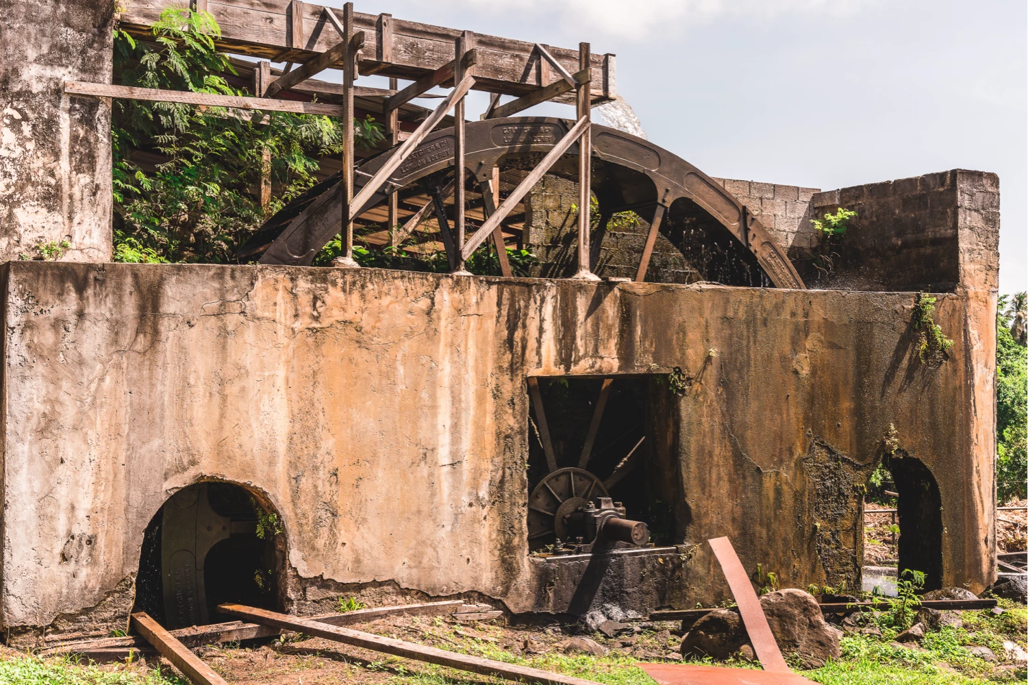 Historic water wheel sugarcane mill surrounded by tropical vegetation